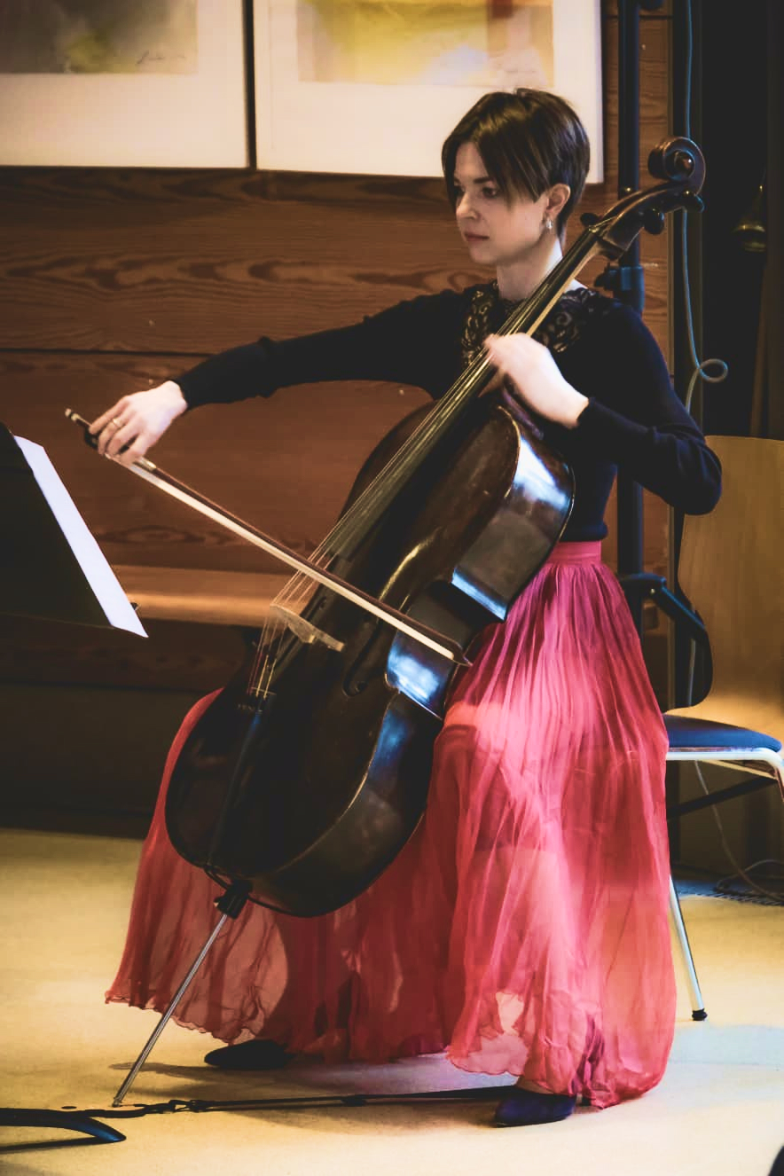 Eine junge Frau in rotem Kleid spielt Cello